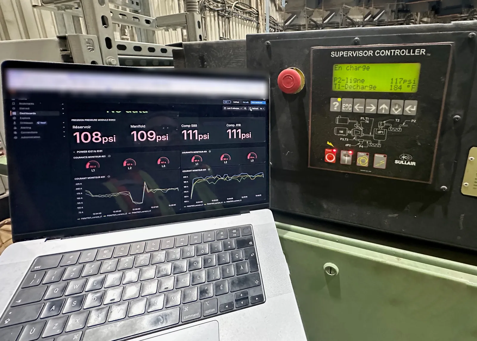 Portable affichant le tableau de bord de mesurage en direct (pressions et courants), devant le contrôleur d’un compresseur en usine.